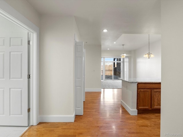 hallway featuring light wood finished floors, recessed lighting, and baseboards