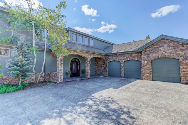 28154 Belle Mont Trl, Conifer, CO 80433 - view of front of home featuring driveway, a garage, stucco siding, a porch, and stone siding