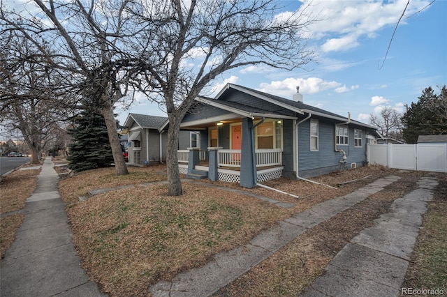 bungalow with a porch, a gate, fence, and a chimney