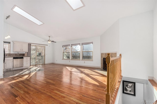 unfurnished living room featuring a skylight, light hardwood / wood-style floors, high vaulted ceiling, and ceiling fan