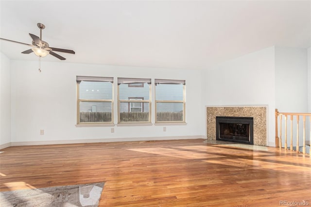 unfurnished living room featuring a premium fireplace, ceiling fan, and light wood-type flooring