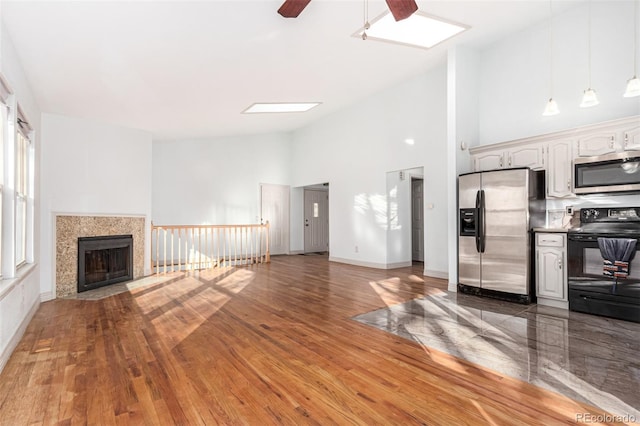 unfurnished living room featuring a high ceiling, dark hardwood / wood-style floors, and ceiling fan