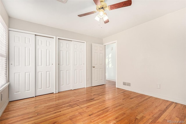 unfurnished bedroom with two closets, light hardwood / wood-style floors, and ceiling fan