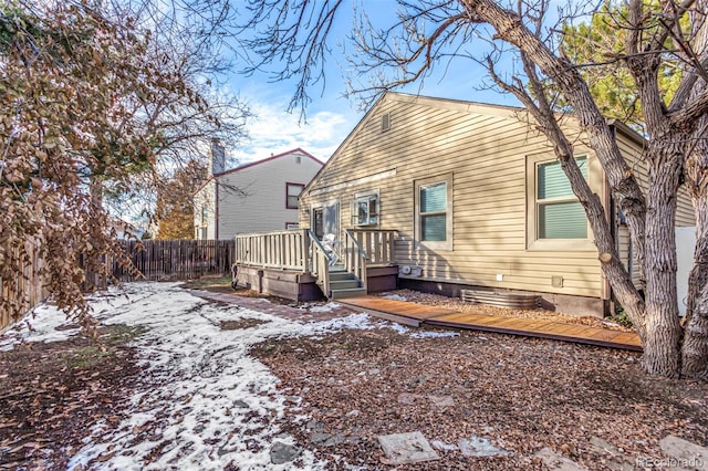 snow covered house featuring a wooden deck