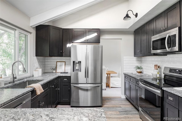 4821 W 102nd Ave, Westminster, CO 80031 - kitchen with appliances with stainless steel finishes, light stone counters, light wood finished floors, backsplash, and vaulted ceiling