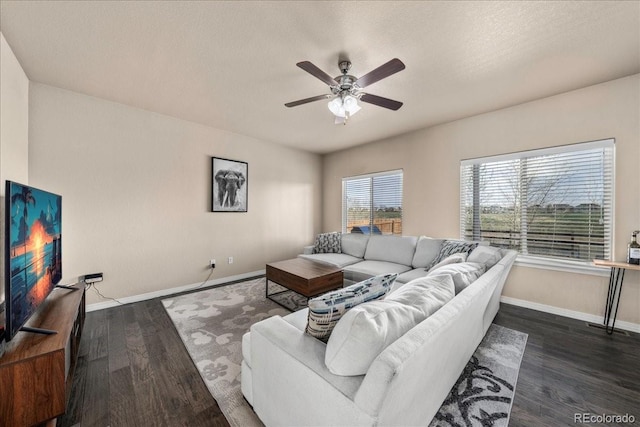 living area featuring baseboards, a textured ceiling, dark wood finished floors, and ceiling fan