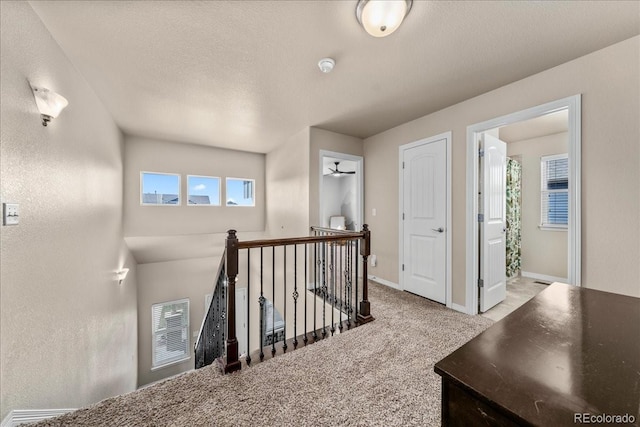 hallway with baseboards, an upstairs landing, and carpet