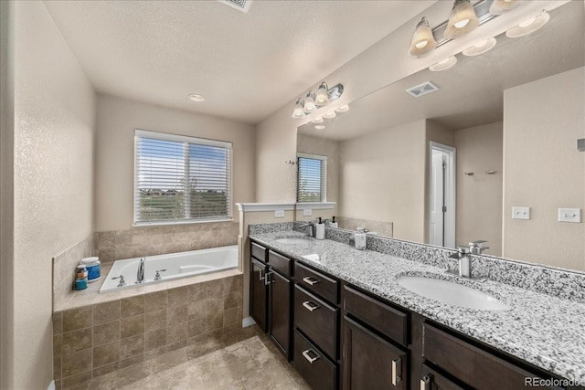 full bath with visible vents, a sink, a bath, and double vanity