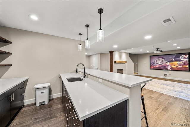 kitchen with visible vents, open shelves, dark wood-type flooring, light countertops, and a sink