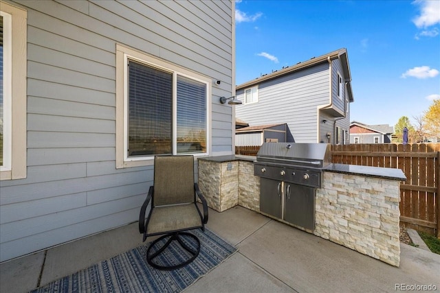 view of patio with fence, area for grilling, and an outdoor kitchen