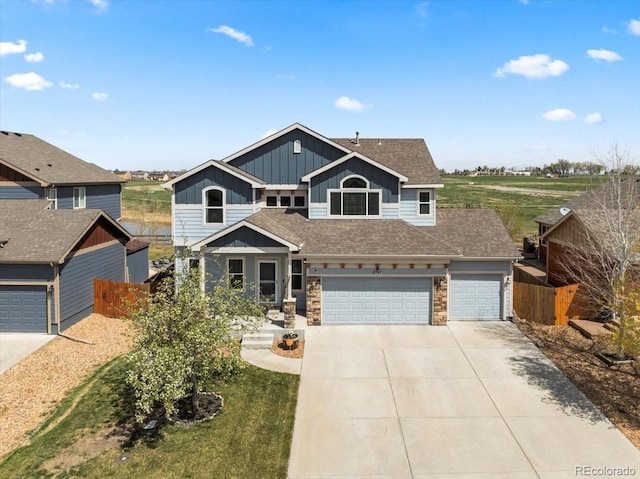 craftsman inspired home featuring board and batten siding, a garage, fence, concrete driveway, and stone siding