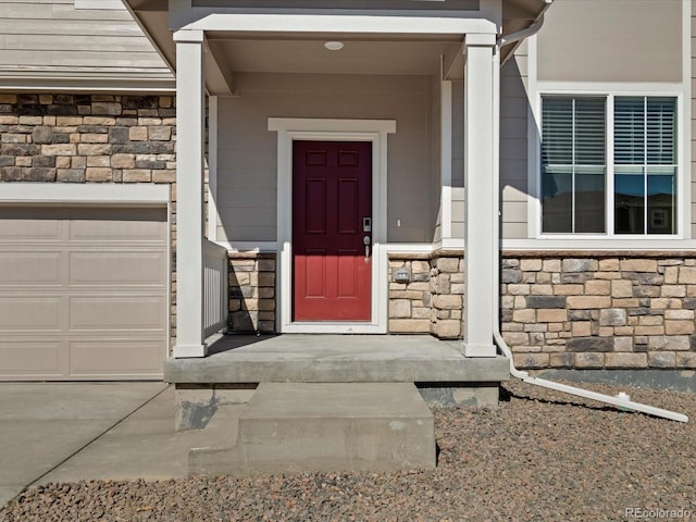 view of exterior entry featuring stone siding and an attached garage