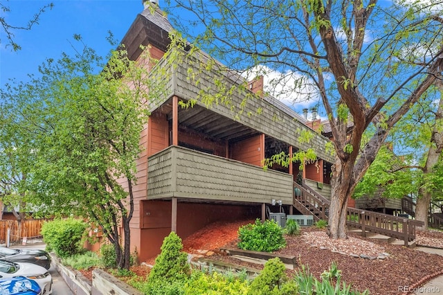 view of side of home with mansard roof, stairway, and fence