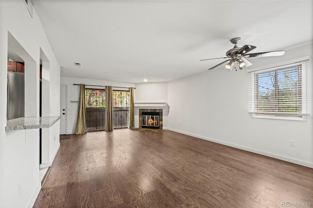 unfurnished living room with dark wood finished floors, plenty of natural light, and baseboards