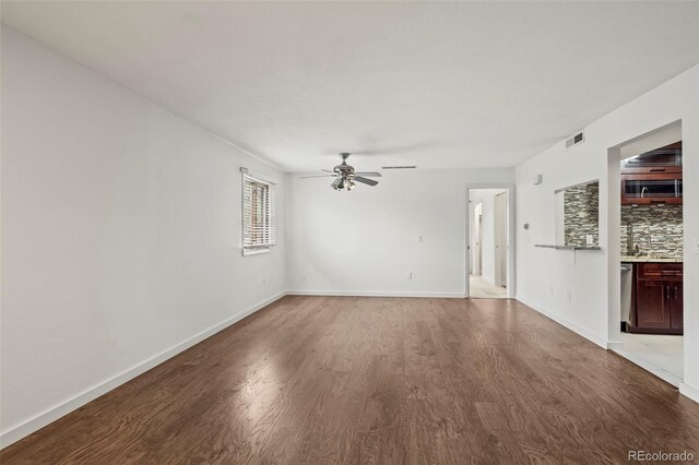 unfurnished living room featuring light wood-type flooring, a ceiling fan, and baseboards