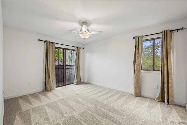 carpeted spare room featuring ceiling fan and baseboards