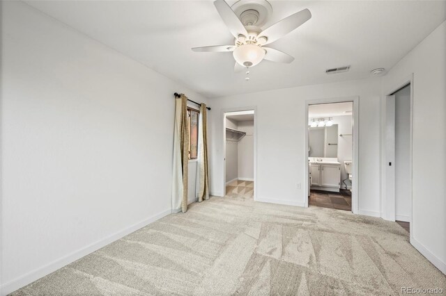 unfurnished bedroom with carpet, baseboards, a walk in closet, ensuite bathroom, and a closet