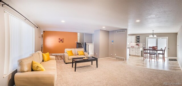 carpeted living room featuring a textured ceiling and a notable chandelier