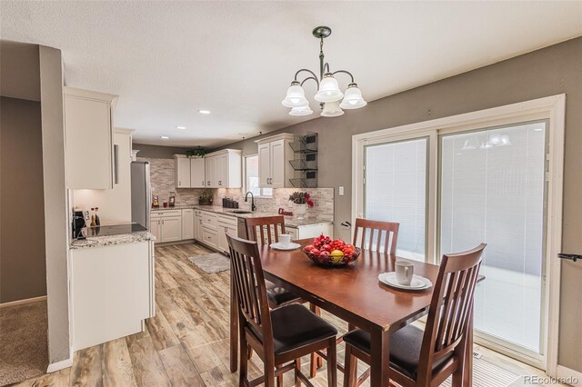 dining area featuring a wealth of natural light, sink, light wood-type flooring, and an inviting chandelier