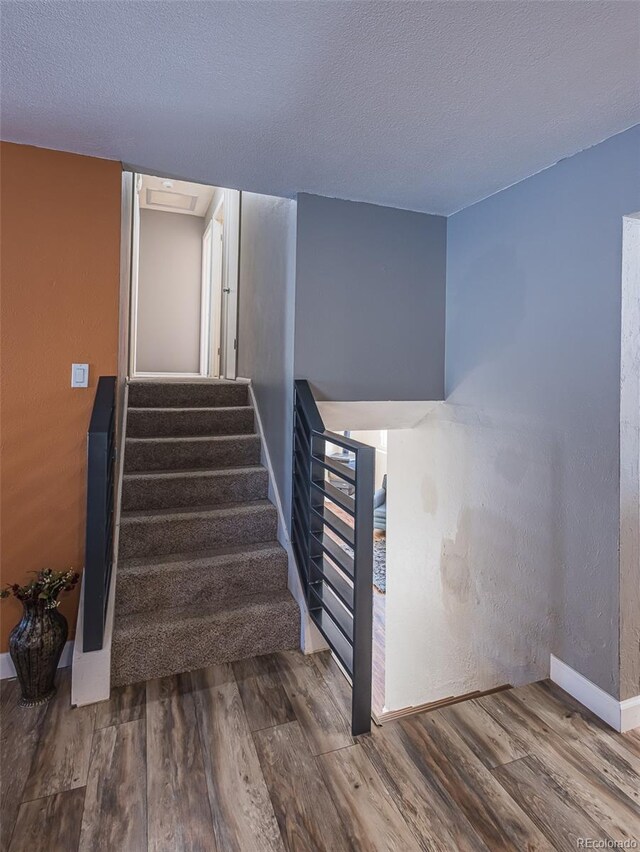 stairs with wood-type flooring and a textured ceiling