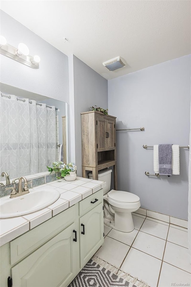 bathroom with tile patterned floors, vanity, toilet, and a textured ceiling