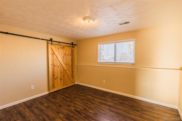 empty room featuring dark hardwood / wood-style flooring and a barn door