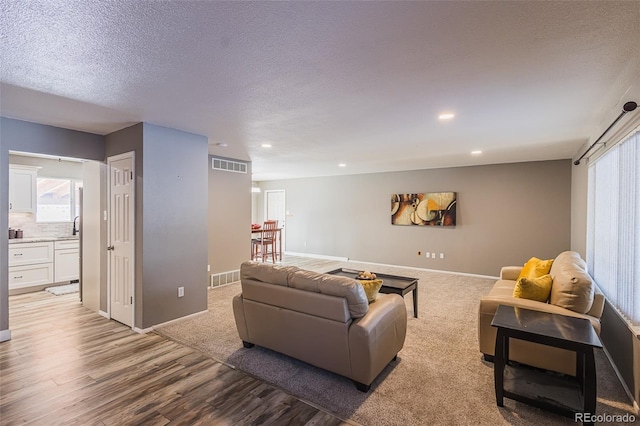 living room with a textured ceiling, light hardwood / wood-style floors, and sink