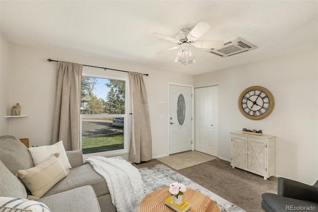 carpeted living room with ceiling fan and a textured ceiling