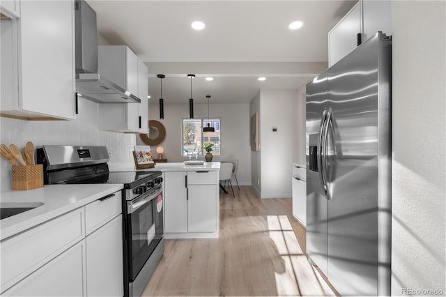 kitchen featuring light wood-style floors, appliances with stainless steel finishes, wall chimney range hood, and white cabinetry