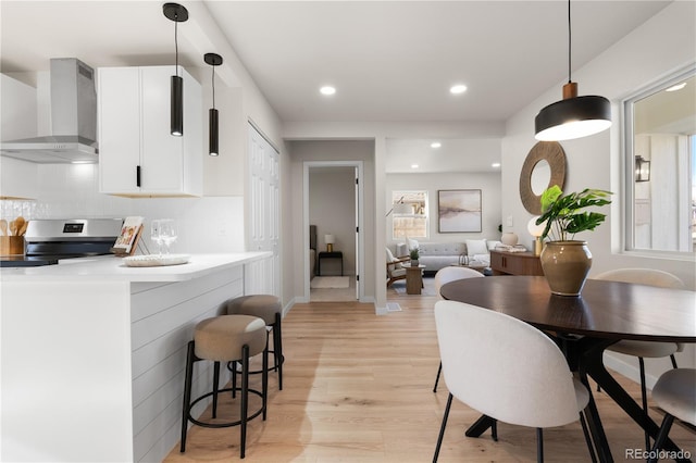 dining space with baseboards, light wood finished floors, and recessed lighting
