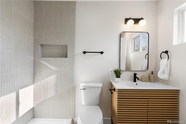 full bathroom featuring tiled shower, vanity, and toilet