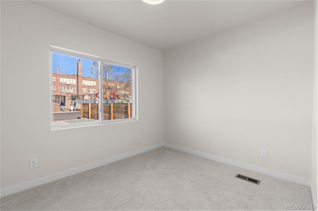 empty room with baseboards, visible vents, and carpet floors
