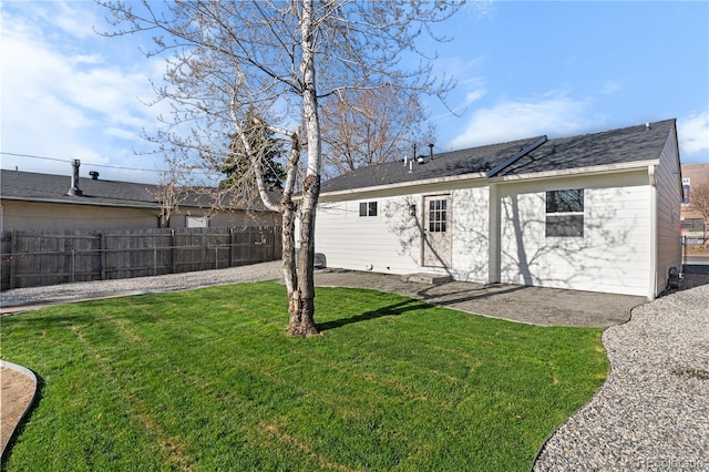 rear view of house with entry steps, fence, and a lawn