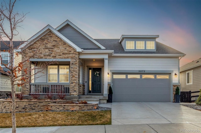 craftsman house featuring driveway, stone siding, a porch, an attached garage, and a shingled roof