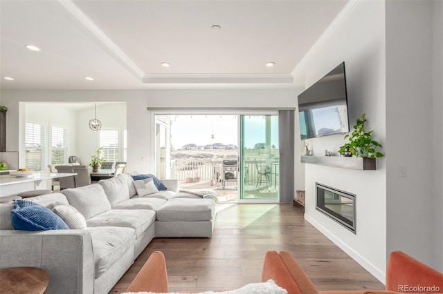 living area with a glass covered fireplace, wood finished floors, recessed lighting, and a healthy amount of sunlight