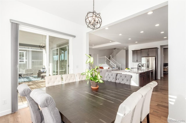 dining room with baseboards, stairs, light wood-type flooring, recessed lighting, and a notable chandelier