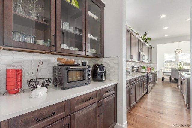 kitchen featuring a toaster, light countertops, dark brown cabinets, light wood-style floors, and appliances with stainless steel finishes