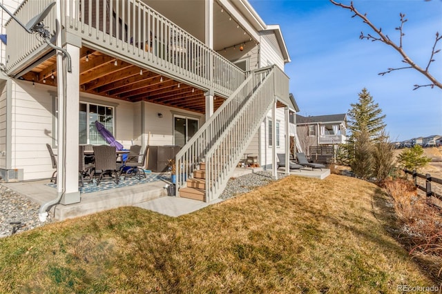 back of house with stairway, a patio, and a lawn