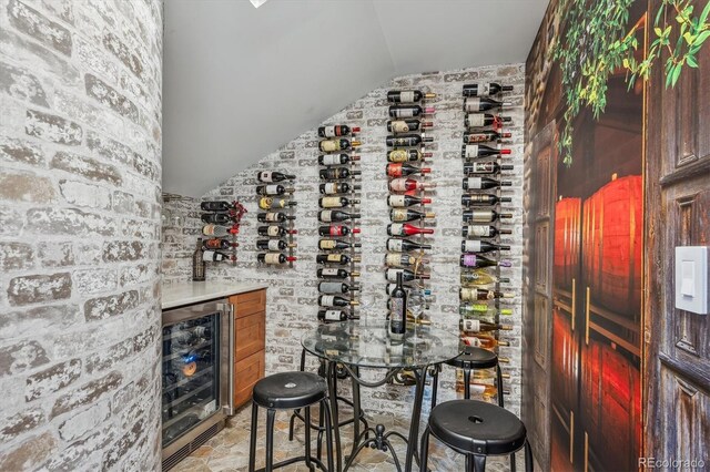 8717 Ridgepoint Dr, Castle Pines, CO 80108 - wine area featuring beverage cooler, vaulted ceiling, and light stone finish floors