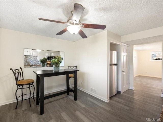 dining room with ceiling fan, dark hardwood / wood-style flooring, and a textured ceiling