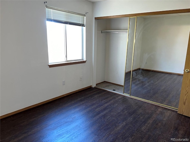 unfurnished bedroom featuring a closet and dark hardwood / wood-style flooring