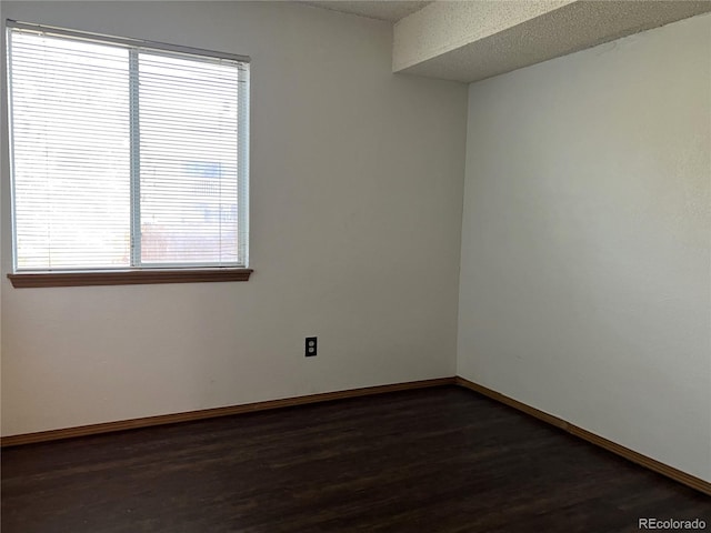 spare room with dark hardwood / wood-style flooring, plenty of natural light, and a textured ceiling