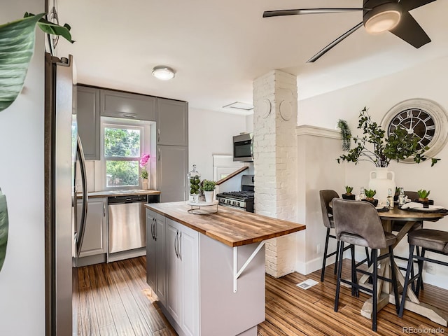 2329 S Gilpin St, Denver, CO 80210 - kitchen with wood counters, stainless steel appliances, ornate columns, gray cabinets, and dark wood-style floors