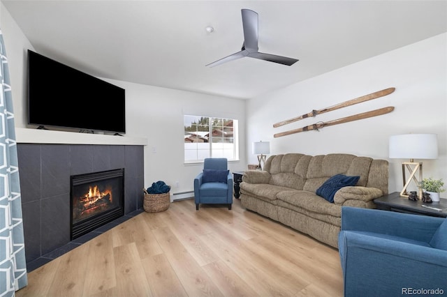 living area featuring a baseboard heating unit, a fireplace, a ceiling fan, and wood finished floors