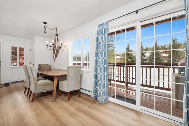 dining area featuring baseboard heating, wood finished floors, and an inviting chandelier