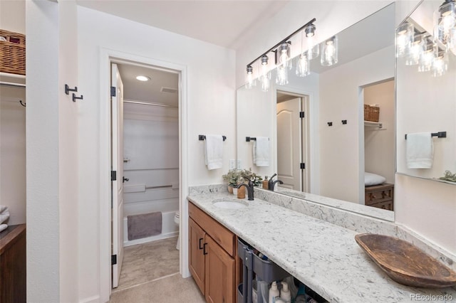 bathroom with double vanity, a spacious closet, a sink, and toilet