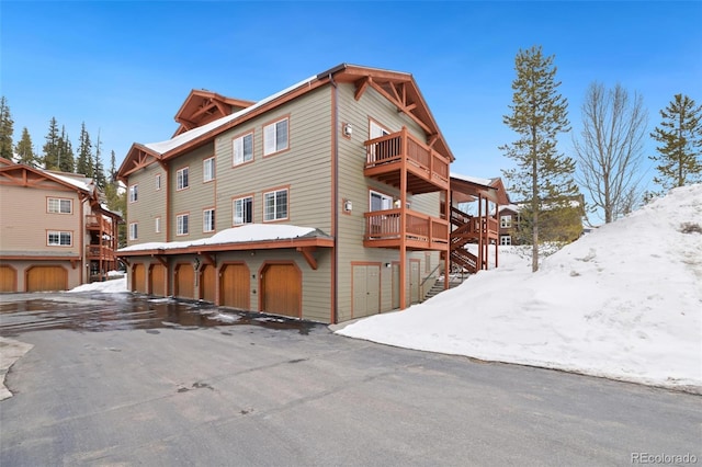 snow covered house featuring a balcony and stairs