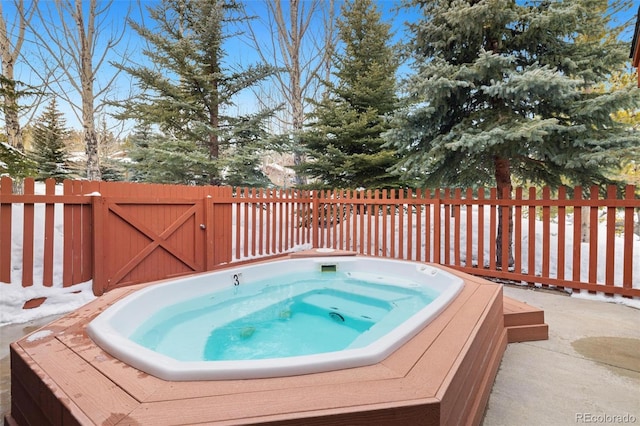 view of swimming pool with fence and hot tub deck surround