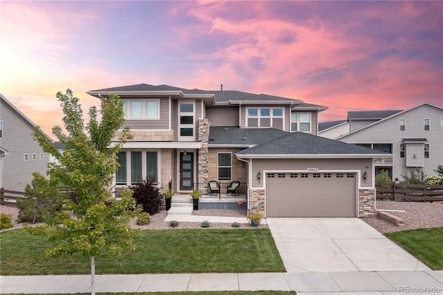 prairie-style home with stone siding, driveway, a garage, and fence