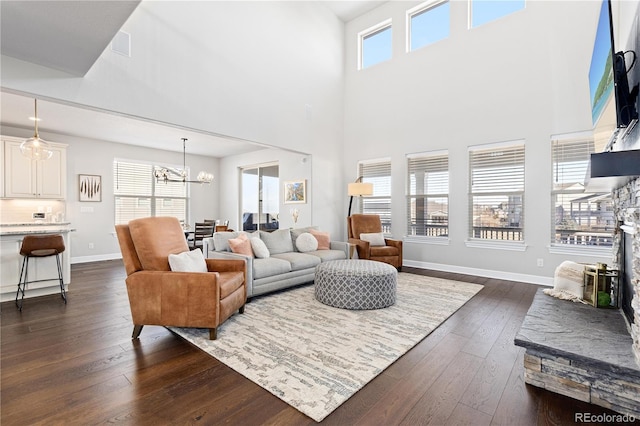 living area featuring baseboards, plenty of natural light, a notable chandelier, and dark wood finished floors